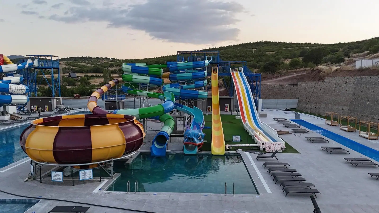 Balıkesir'de teslim edilen aquaparkın akşam saatlerinde geniş görünümü: kâse, kaydırak hatları ve havuzlar
